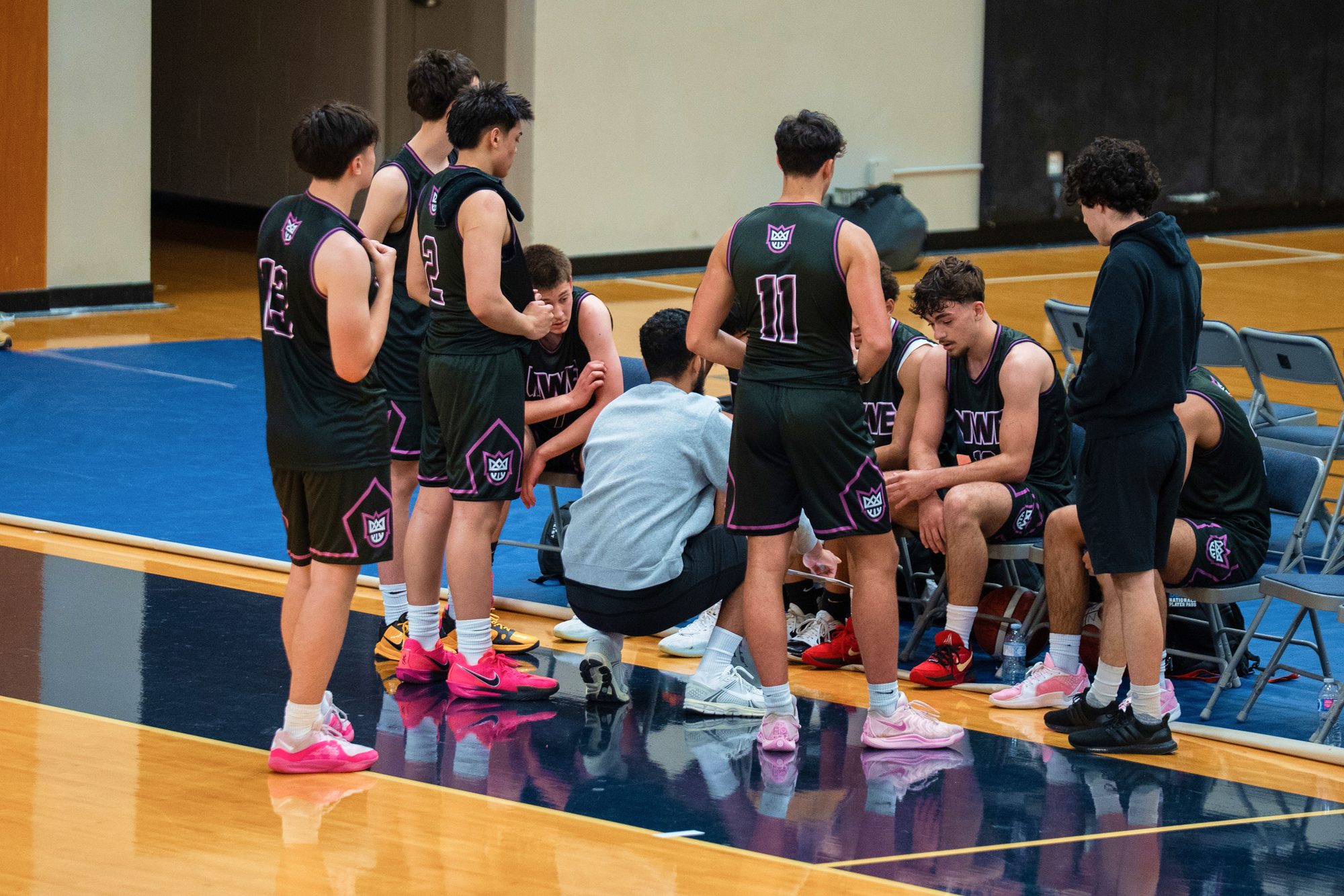 New West Elite players in uniform huddled with their coach on the sideline